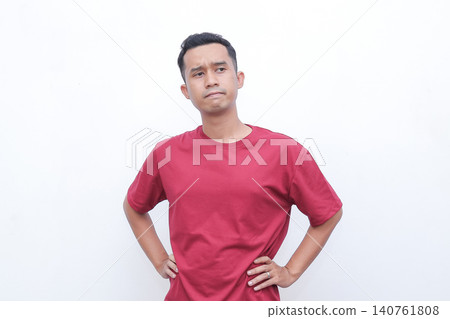 Man shrugs, hands open, showing uncertainty. He wears a simple red tshirt. His expression suggests confusion or indifference. Ideal for situations requiring a gesture of hesitation Man shrugs, hands open, showing uncertainty. He wears a simple red tshirt. His expression suggests confusion or indifference. Ideal for situations requiring a gesture of hesitation 140761808