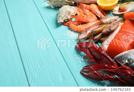 Fresh fish and different seafood on blue wooden table. Space for text Fresh fish and different seafood on blue wooden table. Space for text 140762165