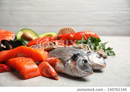 Fresh fish and different seafood on light grey table, closeup Fresh fish and different seafood on light grey table, closeup 140762166
