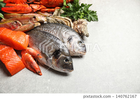 Fresh raw fish and different seafood on light grey table. Space for text Fresh raw fish and different seafood on light grey table. Space for text 140762167