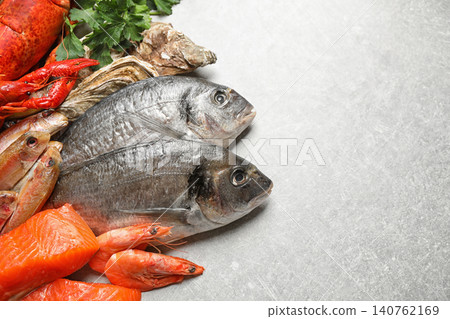 Fresh raw fish and different seafood on light grey table. Space for text Fresh raw fish and different seafood on light grey table. Space for text 140762169