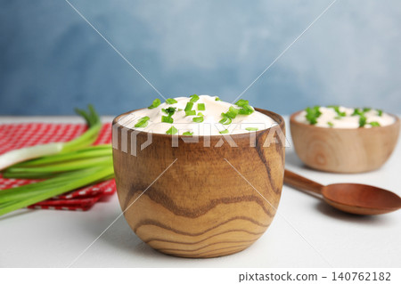 Fresh sour cream with onion on white table against light blue background Fresh sour cream with onion on white table against light blue background 140762182