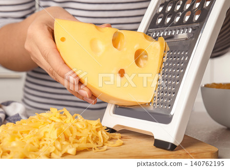 Woman grating fresh cheese at table, closeup 140762195
