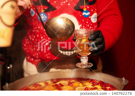 Seller pouring tasty mulled wine into cup at winter fair, closeup 140762278