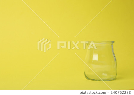 Open empty glass jar on light yellow background, space for text Open empty glass jar on light yellow background, space for text 140762288