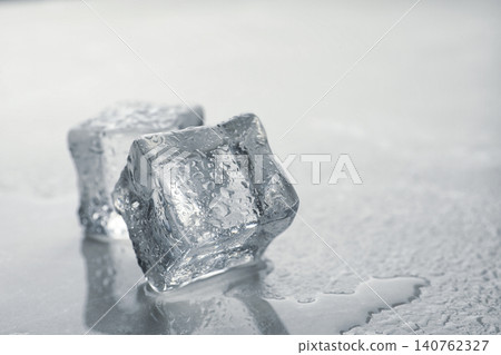 Crystal clear ice cubes with water drops on grey table, closeup. Space for text Crystal clear ice cubes with water drops on grey table, closeup. Space for text 140762327