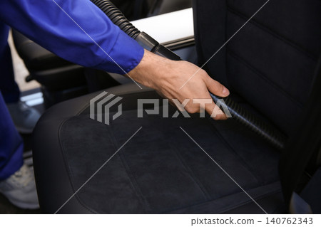 Car wash worker vacuuming automobile seat, closeup Car wash worker vacuuming automobile seat, closeup 140762343