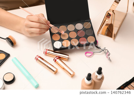 Beauty blogger with brush and eyeshadow palette at table, closeup Beauty blogger with brush and eyeshadow palette at table, closeup 140762346