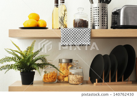Wooden shelves with dishware and products on white wall. Kitchen interior idea Wooden shelves with dishware and products on white wall. Kitchen interior idea 140762430