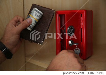 Man putting passport and money into small steel safe, closeup Man putting passport and money into small steel safe, closeup 140762496