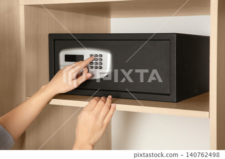 Woman opening black steel safe with electronic lock at hotel, closeup Woman opening black steel safe with electronic lock at hotel, closeup 140762498