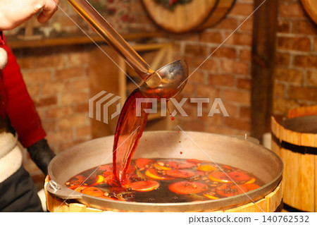 Seller pouring tasty aromatic mulled wine at winter fair, closeup 140762532