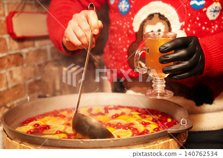 Seller filling cup with tasty mulled wine at winter fair, closeup 140762534