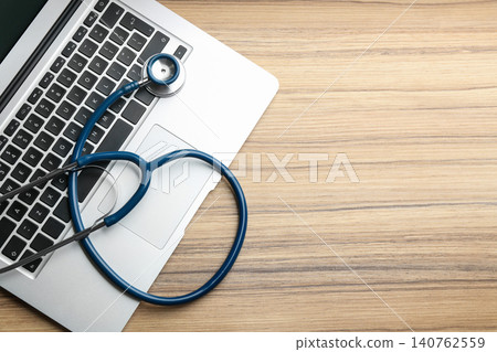 Laptop and stethoscope on wooden table, flat lay with space for text. Concept of technical support Laptop and stethoscope on wooden table, flat lay with space for text. Concept of technical support 140762559