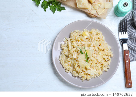 Delicious risotto with cheese on white wooden table, flat lay Delicious risotto with cheese on white wooden table, flat lay 140762632
