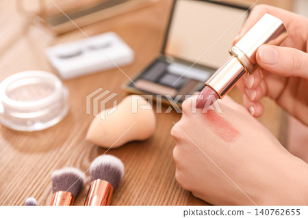 Beauty blogger doing lipstick swatch at table, closeup 140762655