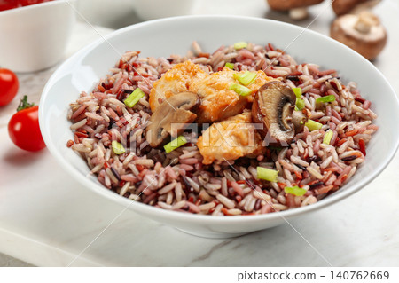 Tasty brown rice with chicken and mushrooms on table, closeup Tasty brown rice with chicken and mushrooms on table, closeup 140762669