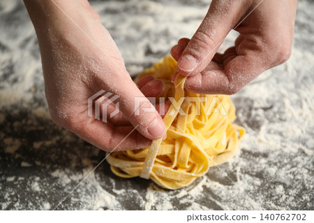 Woman holding pasta at table, closeup view Woman holding pasta at table, closeup view 140762702