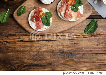 Puffed rice cakes with prosciutto, tomato and basil on wooden table, flat lay. Space for text Puffed rice cakes with prosciutto, tomato and basil on wooden table, flat lay. Space for text 140762785