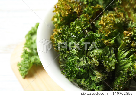 Tasty baked kale chips in bowl on table, closeup Tasty baked kale chips in bowl on table, closeup 140762893
