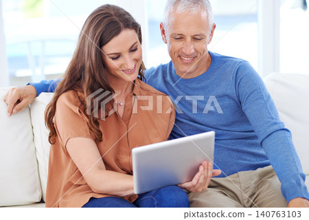 Couple, tablet and smile on sofa to relax with reading, search and app to watch movie with bonding. People, woman and mature man on digital touchscreen for notification with web connection in house Couple, tablet and smile on sofa to relax with reading, search and app to watch movie with bonding. People, woman and mature man on digital touchscreen for notification with web connection in house 140763103