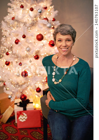 Christmas, tree and portrait of mature woman in home for holiday with presents on vacation. Happy, person and relax on with festive xmas decoration and gift box in living room and enjoy retirement Christmas, tree and portrait of mature woman in home for holiday with presents on vacation. Happy, person and relax on with festive xmas decoration and gift box in living room and enjoy retirement 140763107