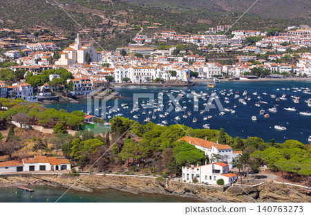 Elevated panoramic view of Cadaques with Santa Maria Church, white Mediterranean houses, and a harbor filled with boats on the Costa Brava, Spain. Elevated panoramic view of Cadaques with Santa Maria Church, white Mediterranean houses, and a harbor filled with boats on the Costa Brava, Spain. 140763273