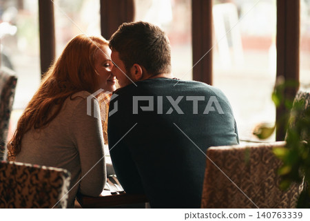 Couple, happiness and kiss on date at restaurant for bonding, romance or healthy relationship with rear view. Man, woman and affection at coffee shop with smile, trust or love on anniversary vacation Couple, happiness and kiss on date at restaurant for bonding, romance or healthy relationship with rear view. Man, woman and affection at coffee shop with smile, trust or love on anniversary vacation 140763339