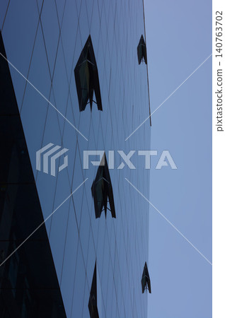 Glass building windows reflecting sky blue Glass building windows reflecting sky blue 140763702