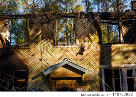 Chevron-paneled house facade partially incinerated, its burnt windows exposing vibrant fall trees. A haunting scene of loss Chevron-paneled house facade partially incinerated, its burnt windows exposing vibrant fall trees. A haunting scene of loss 140763998