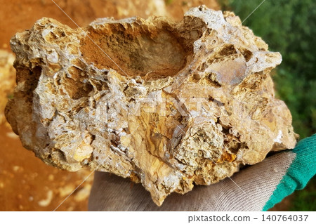 Intricate flint rock held by a gloved hand, showcasing unique geological patterns and rough textures under natural light Intricate flint rock held by a gloved hand, showcasing unique geological patterns and rough textures under natural light 140764037