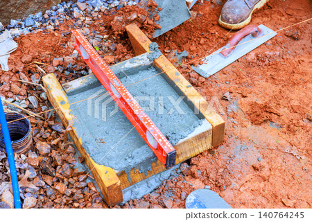 Workers level concrete slab with tools materials at construction site. 140764245