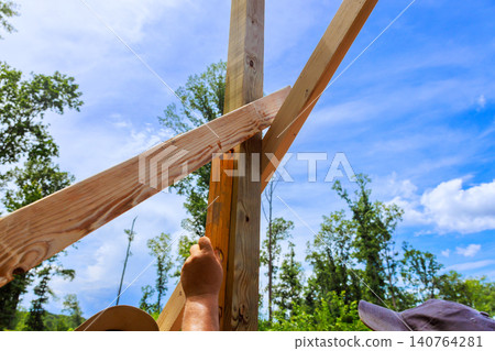 Two workers are engaged in construction, using level tool with wooden beams Two workers are engaged in construction, using level tool with wooden beams 140764281