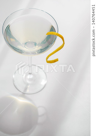 Martini cocktail with lemon zest garnish on white background Martini cocktail with lemon zest garnish on white background 140764451