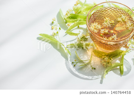 Linden tea in a glass cup with tilia blossoms Linden tea in a glass cup with tilia blossoms 140764458