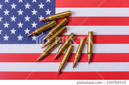 Assault rifle cartridges on the US flag, serving as a conceptual backdrop for defense Assault rifle cartridges on the US flag, serving as a conceptual backdrop for defense 140764534