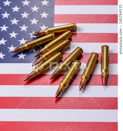 Assault rifle cartridges on the US flag, serving as a conceptual backdrop for defense Assault rifle cartridges on the US flag, serving as a conceptual backdrop for defense 140764535