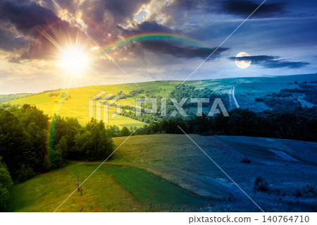 rural fields near mountain in summertime. day meet night. beautiful view of agricultural area. sun and moon in harmony over gorgeous mountain ridge with haystack on a grassy pasture. summer solstice rural fields near mountain in summertime. day meet night. beautiful view of agricultural area. sun and moon in harmony over gorgeous mountain ridge with haystack on a grassy pasture. summer solstice 140764710