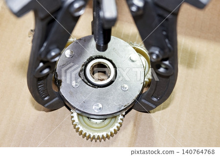 Three-jaw puller removing a sprag clutch from an electric bike geared motor, DIY maintenance of e-bike hub motor internals, industrial workshop repair process, close-up shot Three-jaw puller removing a sprag clutch from an electric bike geared motor, DIY maintenance of e-bike hub motor internals, industrial workshop repair process, close-up shot 140764768