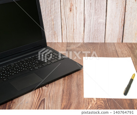 black laptop and sheet of paper with pen on table 140764791
