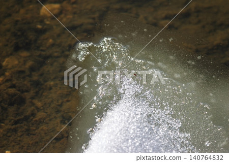 Sun-drenched melting ice on a river's edge, fizzing with bubbles. A pristine view of spring's gentle thaw, nature's rebirth Sun-drenched melting ice on a river's edge, fizzing with bubbles. A pristine view of spring's gentle thaw, nature's rebirth 140764832