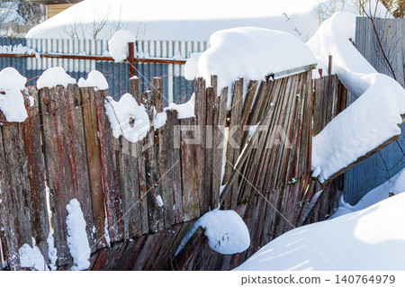 Weathered wooden fence heavily laden with pristine white snow under a bright winter sun. Rustic charm, tranquil frosty landscape Weathered wooden fence heavily laden with pristine white snow under a bright winter sun. Rustic charm, tranquil frosty landscape 140764979