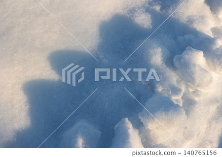 Delicate snow texture shimmering under golden evening light. Soft white powder and cool blue shadows create a serene winter pattern Delicate snow texture shimmering under golden evening light. Soft white powder and cool blue shadows create a serene winter pattern 140765156