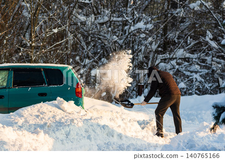 Man vigorously shoveling deep snow, clearing a path for his teal car on a bright winter day after heavy snowfall. Balkan cyclone Francis in Central Russia, January 2026 Man vigorously shoveling deep snow, clearing a path for his teal car on a bright winter day after heavy snowfall. Balkan cyclone Francis in Central Russia, January 2026 140765166