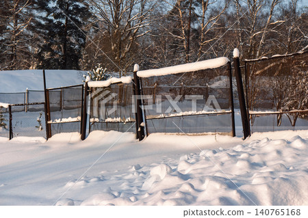 Freshly fallen snow blankets a winter scene featuring a snow-capped fence bathed in warm evening sunlight, creating sharp shadows and bright highlights Freshly fallen snow blankets a winter scene featuring a snow-capped fence bathed in warm evening sunlight, creating sharp shadows and bright highlights 140765168