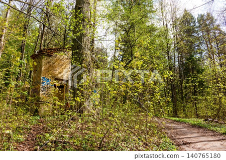 Brick ruins, crumbling yet vibrant with graffiti, nestle amidst lush spring foliage. An eerie, forgotten structure in a serene forest park, blending history and nature: Russia - April 25, 2024 Brick ruins, crumbling yet vibrant with graffiti, nestle amidst lush spring foliage. An eerie, forgotten structure in a serene forest park, blending history and nature: Russia - April 25, 2024 140765180