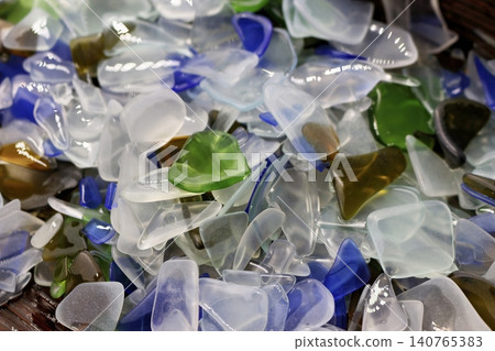 A shimmering heap of vibrant, artificially tumbled glass pieces. Frosted, smooth sea glass replication in blues, greens, and whites, perfect for craft or decor 140765383