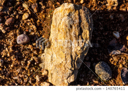 Vibrant flint rock bathed in spring sun, sparkling with tiny quartz crystals. Earthy ground texture, raw mineral beauty 140765411