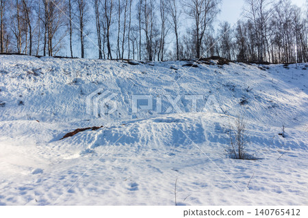 Pristine snow clings to an uneven spring hillside, revealing earthy tones beneath. A picturesque landscape of thawing winter, serene and quiet under a pale sky Pristine snow clings to an uneven spring hillside, revealing earthy tones beneath. A picturesque landscape of thawing winter, serene and quiet under a pale sky 140765412