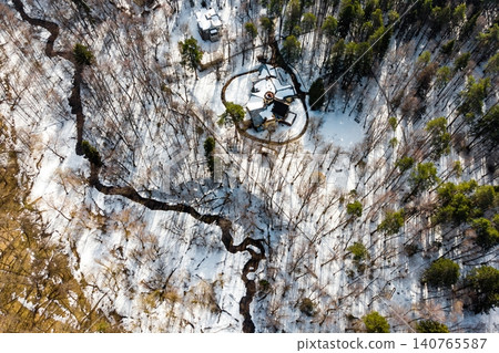 Elegant snow-covered country house nestled in a tranquil winter forest, a winding stream gracefully cuts through the pristine landscape from above Elegant snow-covered country house nestled in a tranquil winter forest, a winding stream gracefully cuts through the pristine landscape from above 140765587